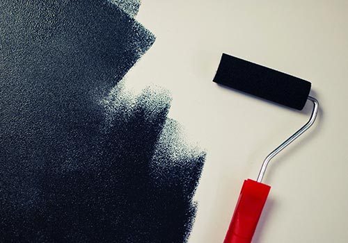 roller painting white wall with navy paint