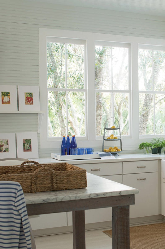 kitchen with big windows, white cabinetry and an island with whicker tray on top